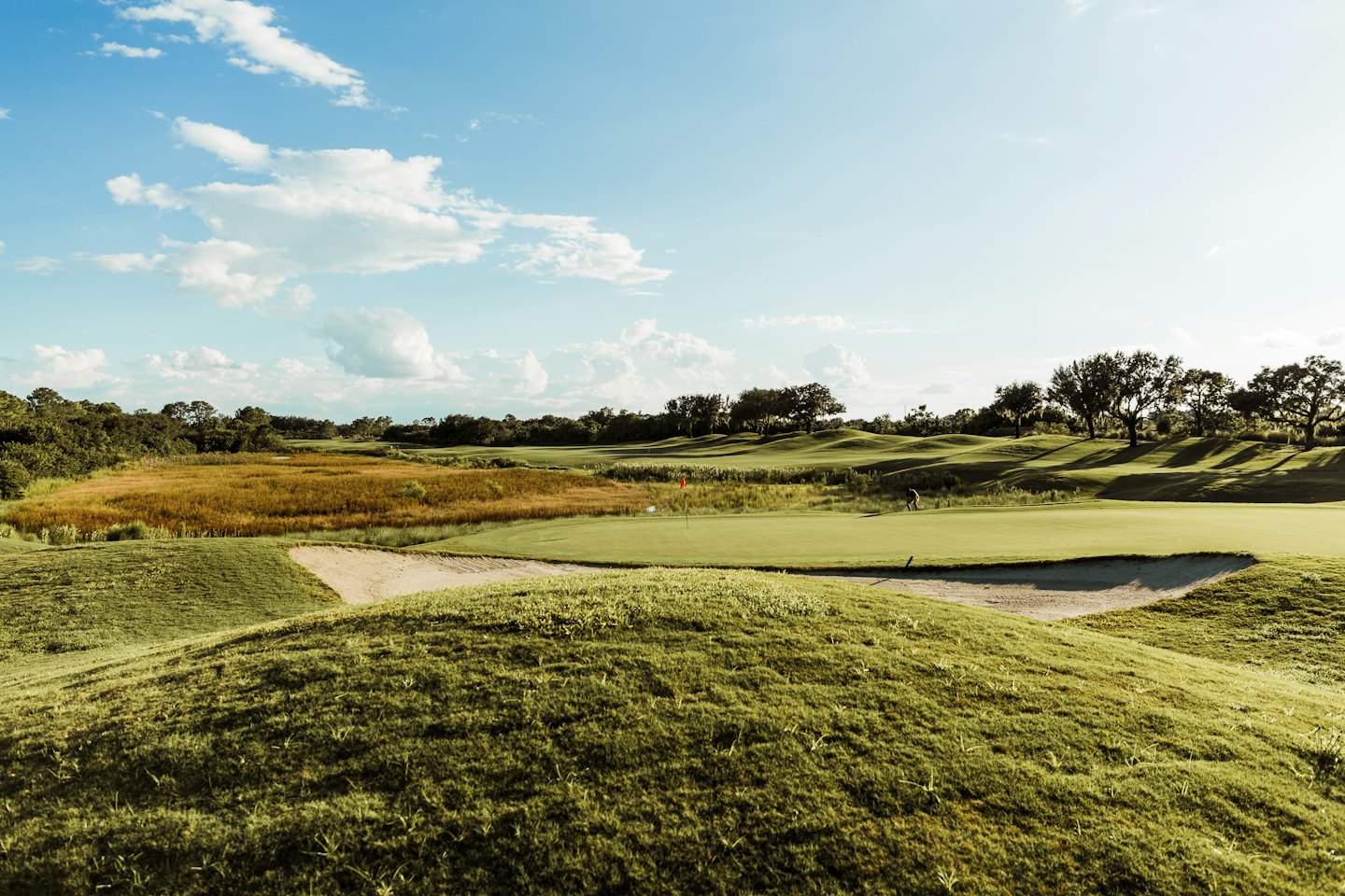 En golfspiller står på putting greenen på en golfbane.