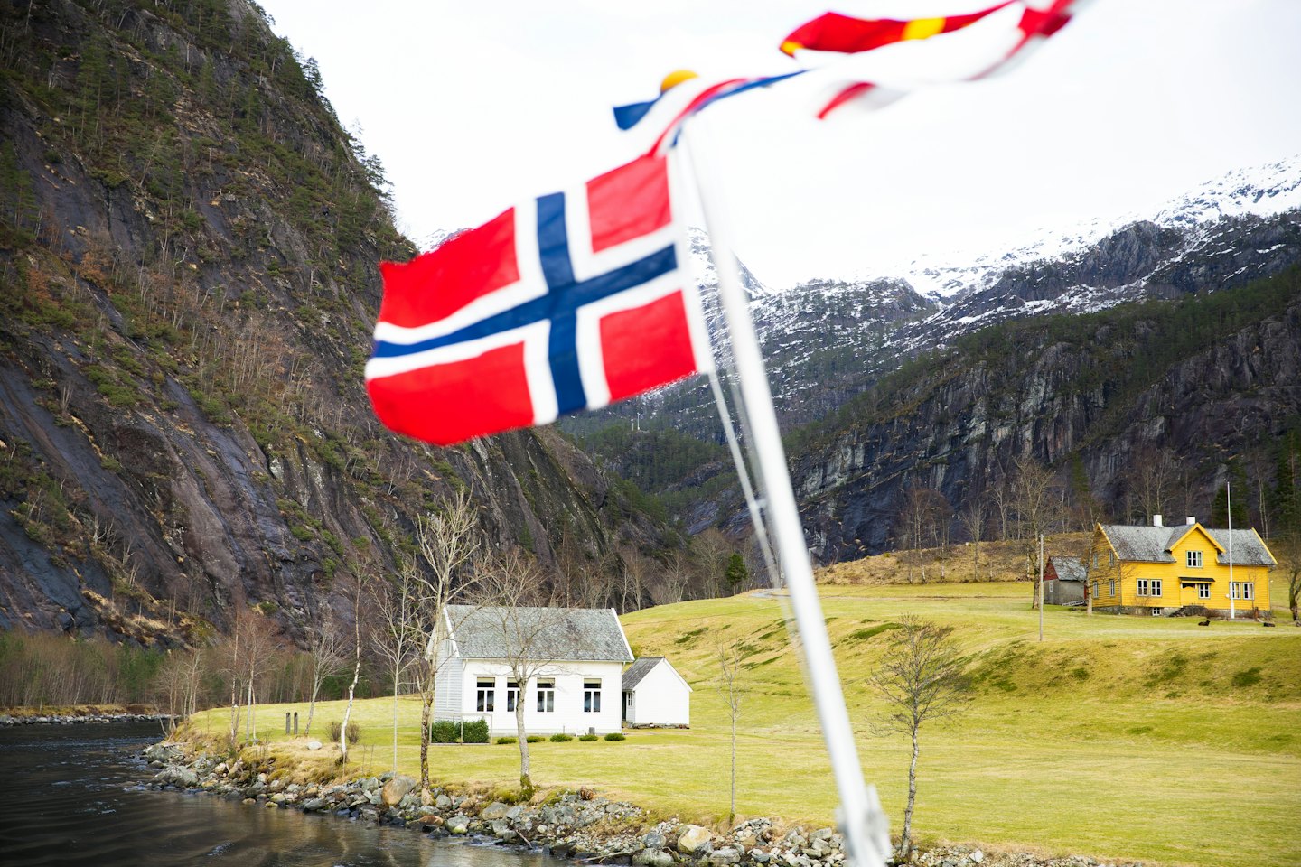 Norgesflagg som vaier foran hus i en fjellside.